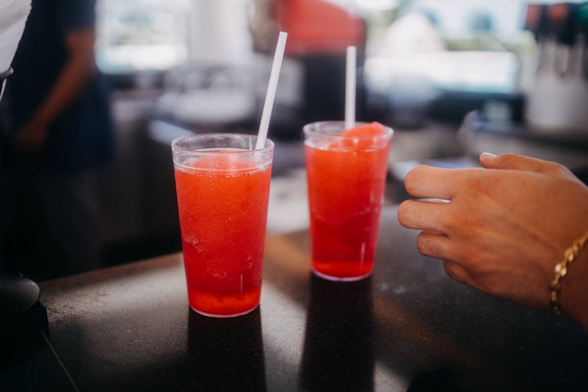 9 Shocking Convenience Store Facts You Need to Know 1 Close-up of two red slushy drinks with straws on a bar counter, indoors and vibrant.