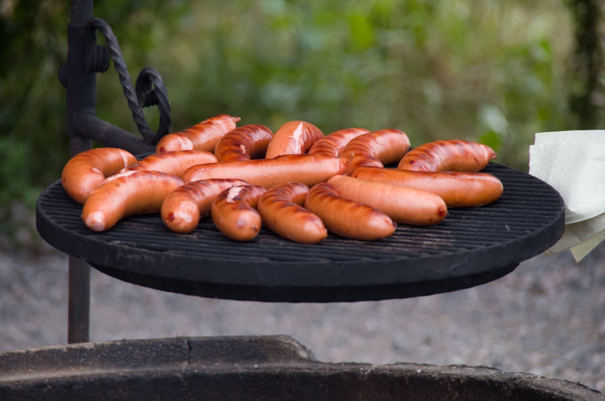 Close-up view of sausages grilling on an outdoor barbecue, perfect for a summer cookout.