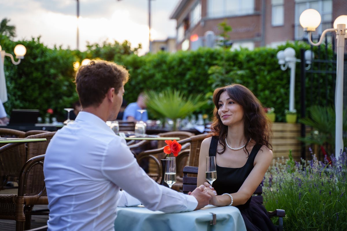 8 Painful Ways People Got Dumped That No One Deserves 2 Couple enjoying a romantic dinner with drinks on an outdoor terrace.