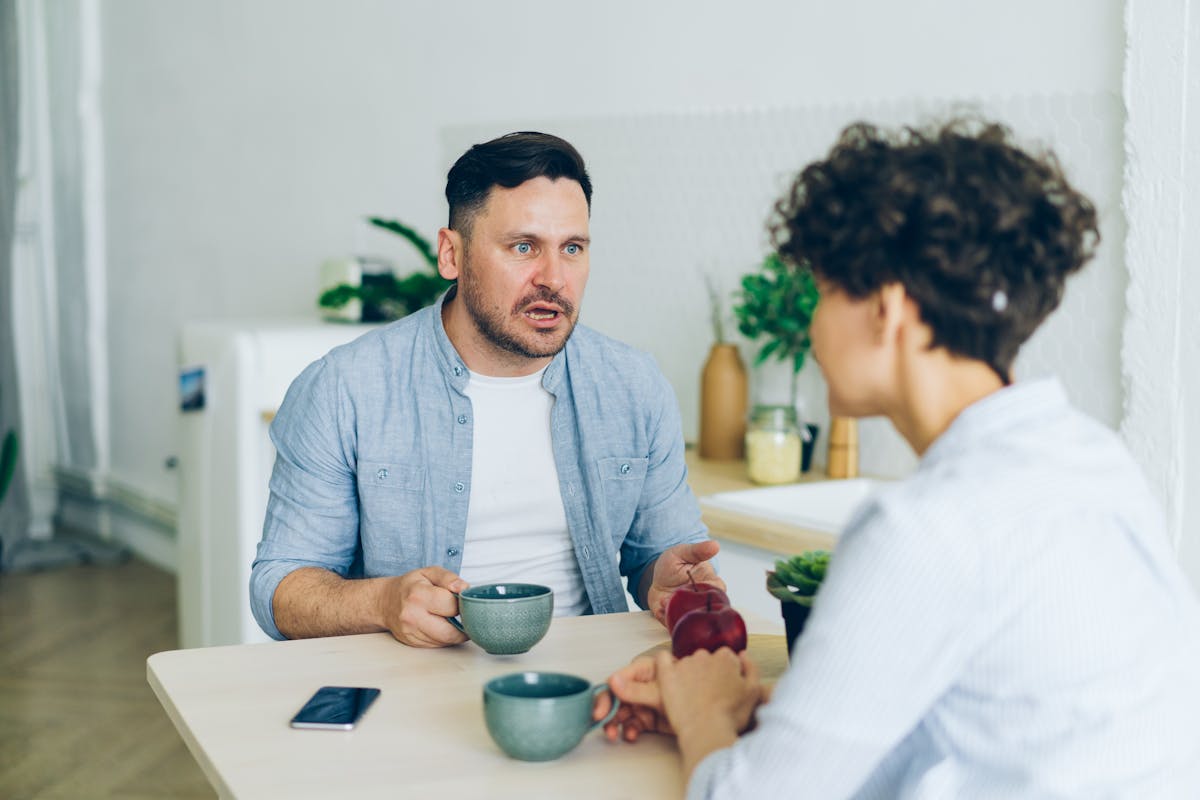 8 Dating Mistakes That Make You Look Desperate 3 Couple having a serious conversation at the kitchen table with coffee cups.