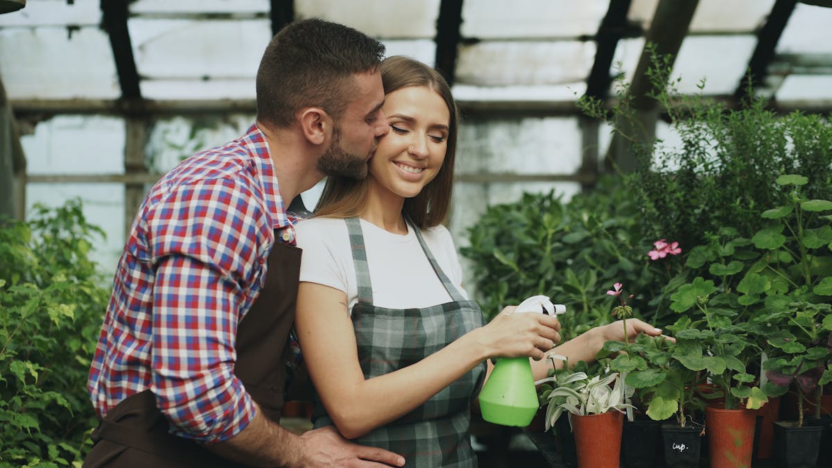 8 Everyday Mistakes That Slowly Undermine Your Marriage 2 Couple joyfully caring for plants in greenhouse, romantic interaction.