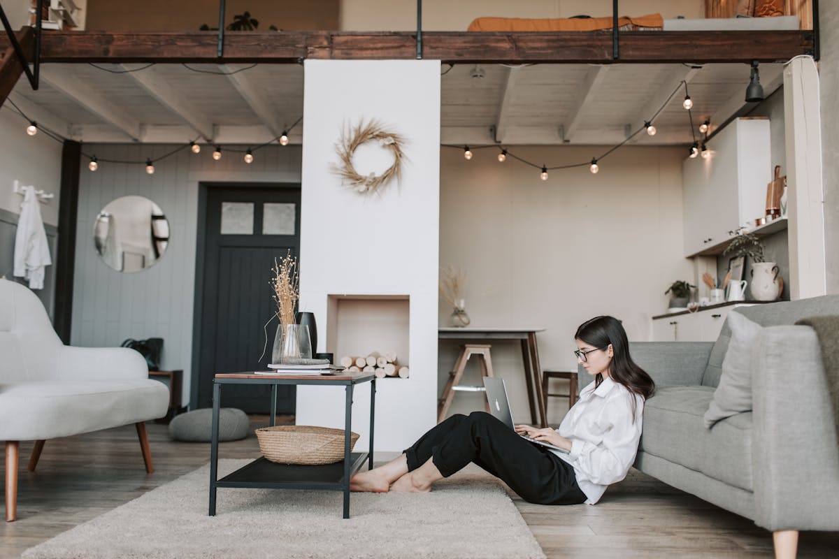 12 Financial Myths to Avoid Teaching Your Adult Children 2 Cozy loft apartment with a woman working on a laptop, showcasing modern remote work lifestyle.