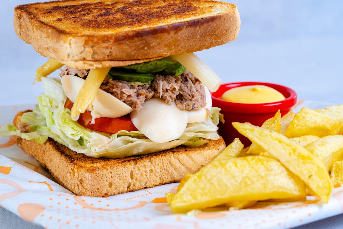 7 Unusual Fast-Food Scandals and Lawsuits That Shook the Industry 2 Delicious sandwich with lettuce, cheese, and fries on a colorful table setting.