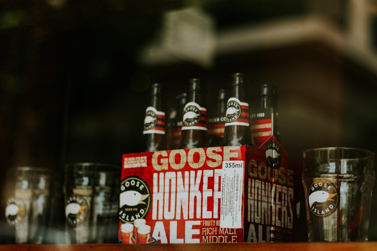 Avoid These 12 Common Bulk Buys 1 Display of Goose Island Honkers Ale beer bottles and glasses with blurred background.