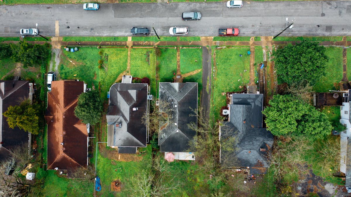 11 Things You Shouldn’t Overlook Before Purchasing a House 4 Drone shot capturing rooftops, greenery, and cars on a quiet urban street.