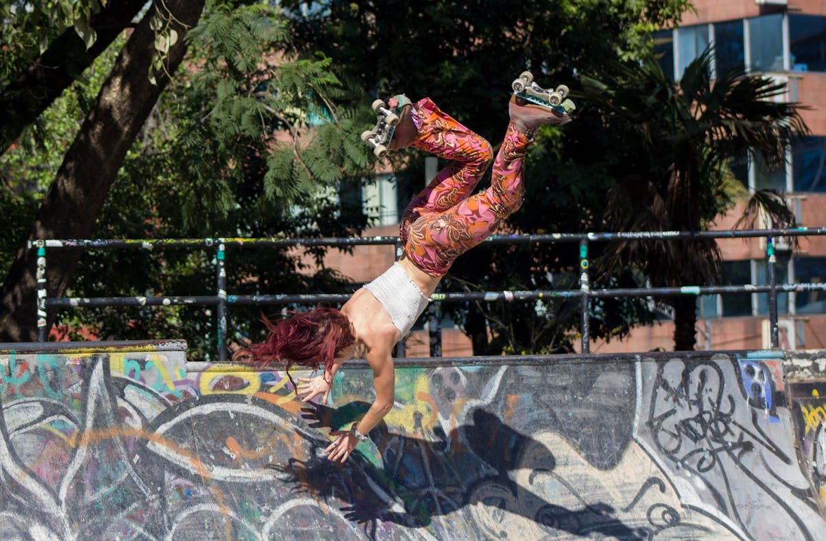 12 Crazy Workouts to Try This Summer That Actually Make Fitness Fun 4 Dynamic shot of a female roller skater doing a handstand trick at an outdoor skate park.