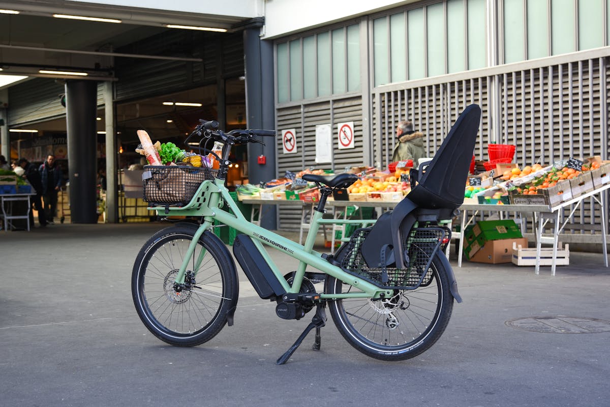 8 Mistakes to Avoid When Purchasing an E-Bike 1 Electric cargo bike loaded with groceries parked outside a market in France, showcasing green urban mobility.