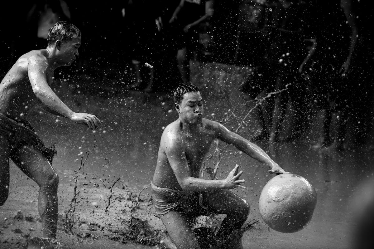 10 Bizarre and Unbelievable Competitions From Around the World 2 Energetic scene of two men playing soccer in the mud, captured in black and white