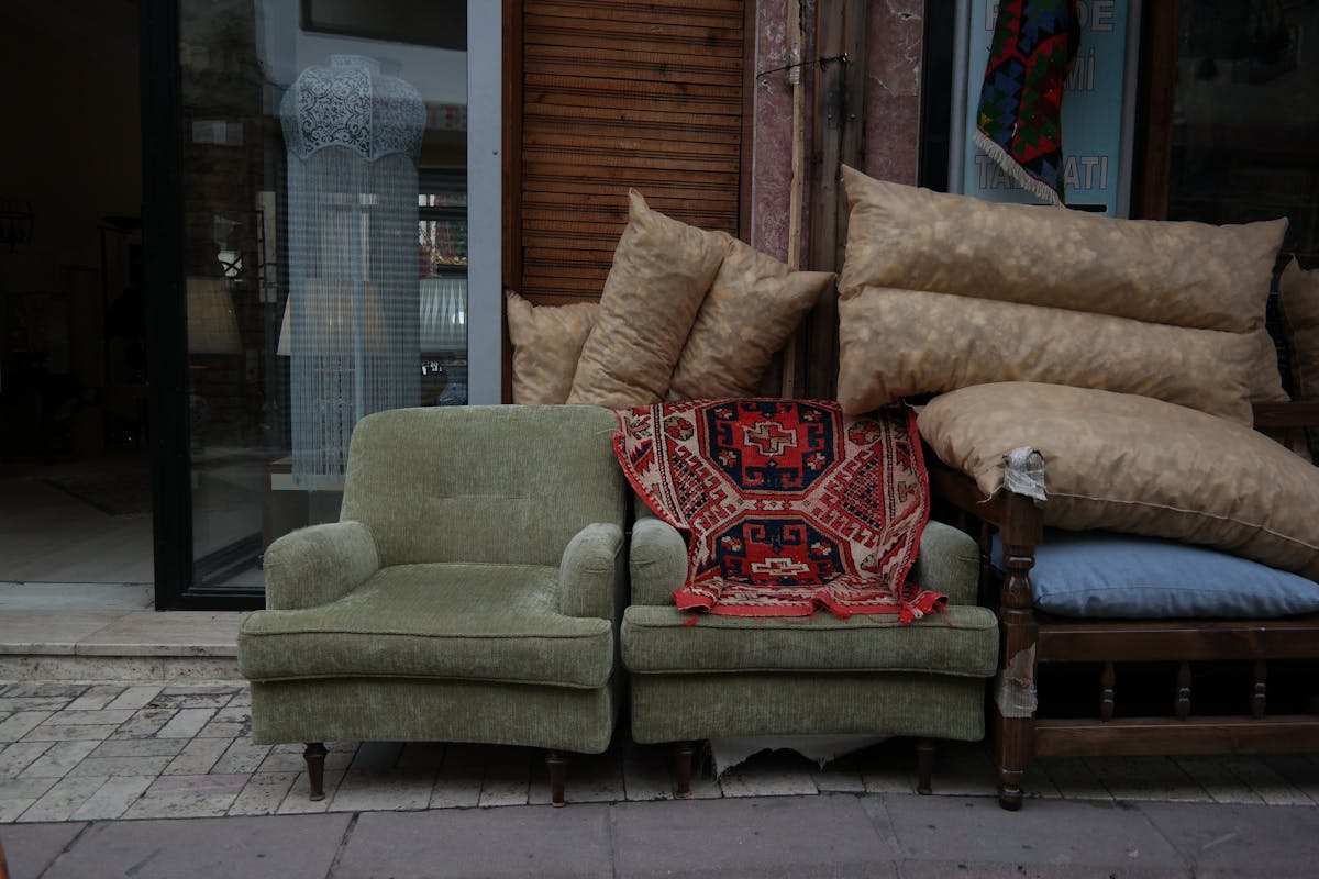 9 Items You Should Never Sell at a Garage Sale 1 Green armchairs with red patterned rug and pillows in Ankara street setting.