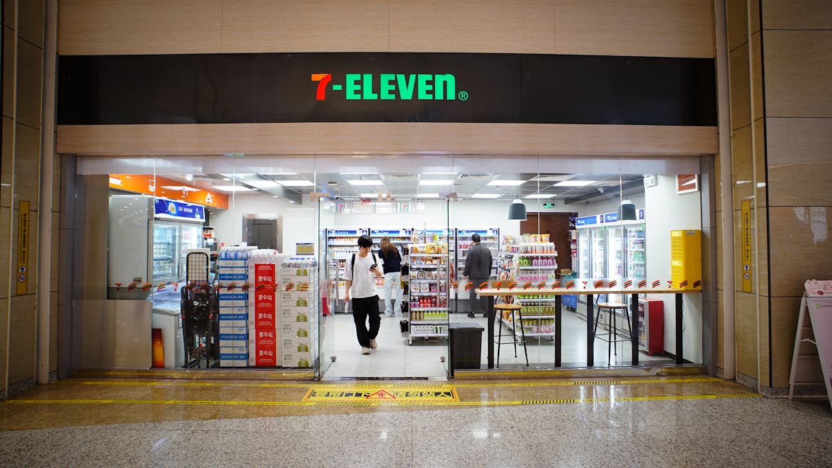 9 Shocking Convenience Store Facts You Need to Know 3 Indoor view of a 7-Eleven store entrance with people shopping and products displayed.
