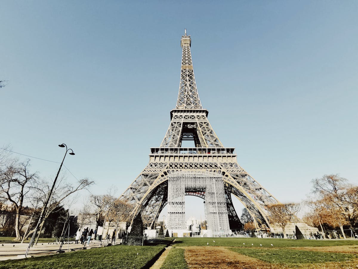 10 Weirdest Facts That Will Blow Your Mind 2 Low angle shot of the Eiffel Tower in Paris with blue sky and partial park view.