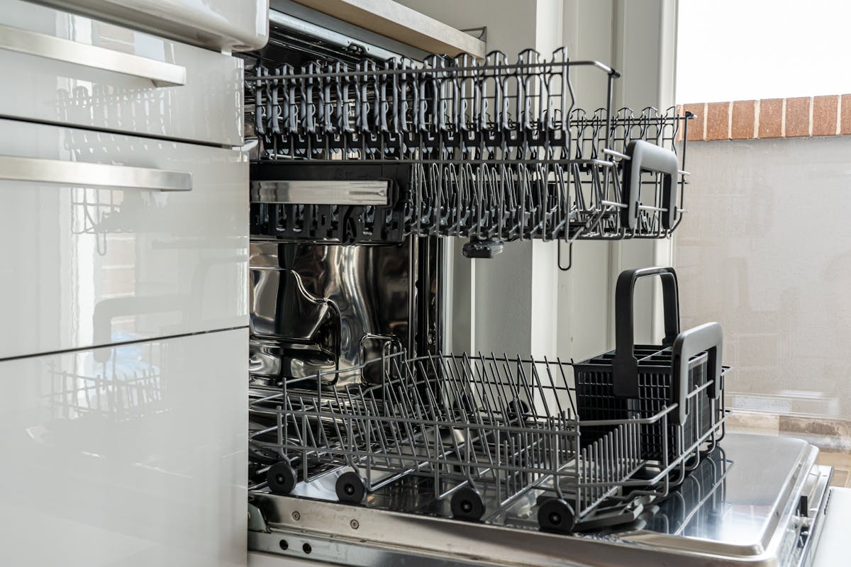 Avoid These 12 Common Bulk Buys 3 Open and empty dishwasher in a sunlit modern kitchen ready for use.