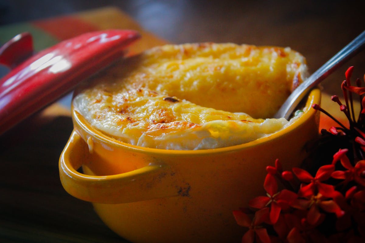 10 Unexpectedly Delicious Recipes With Surprising Ingredients 3 Savory dish topped with melted cheese, served in a yellow pot with a red lid.