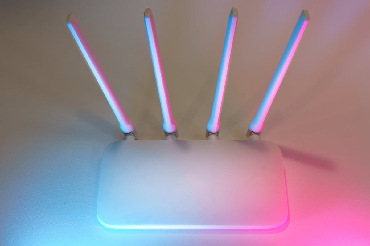 10 Things to Never Pay Full Price For 4 Sleek white wireless router with four antennas emitting soft blue and pink light.