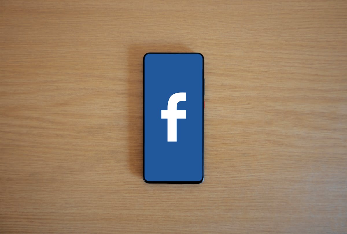 The 9 Most Outrageous Correlations You’ve Never Heard Of 4 Smartphone with Facebook logo on screen, placed on a wooden background. Top view.