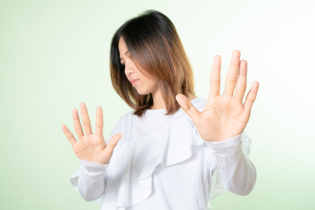 9 Cheap Ways to Boost Your Happiness 2 Studio shot of a woman raising hands in a stop gesture, expressing refusal or no.
