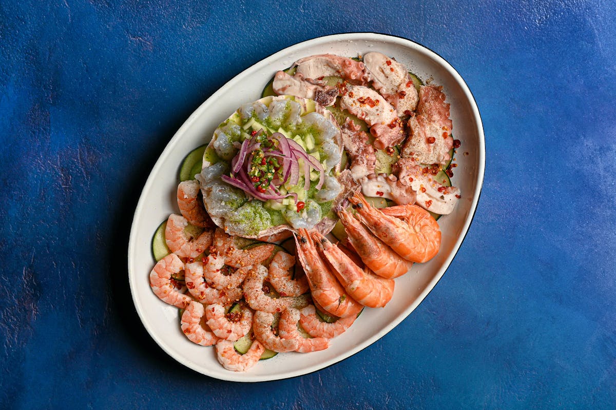 10 Common Allergies That You Shouldn’t Ignore 3 Top view of a fresh seafood platter featuring shrimp and octopus on a blue background.