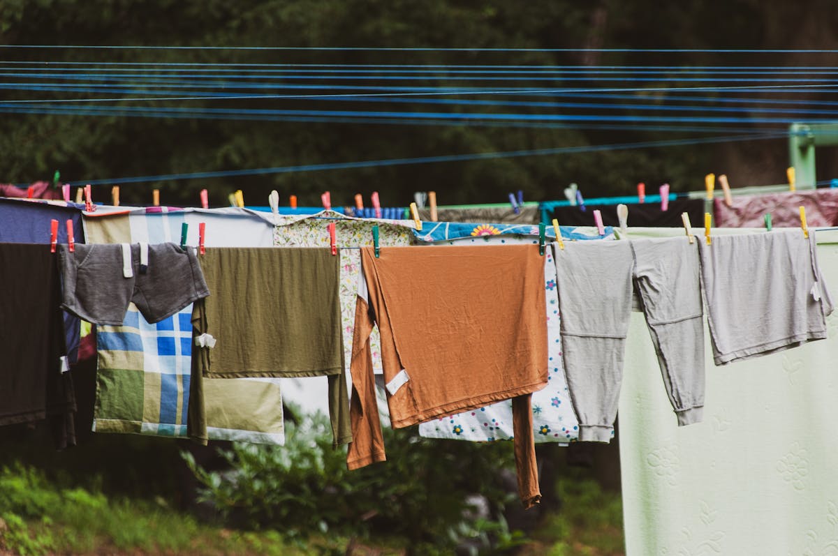 11 Laundry Mistakes to Avoid 4 Vibrant clothes hanging on a clothesline outdoors in a lush green setting, creating a rustic charm.