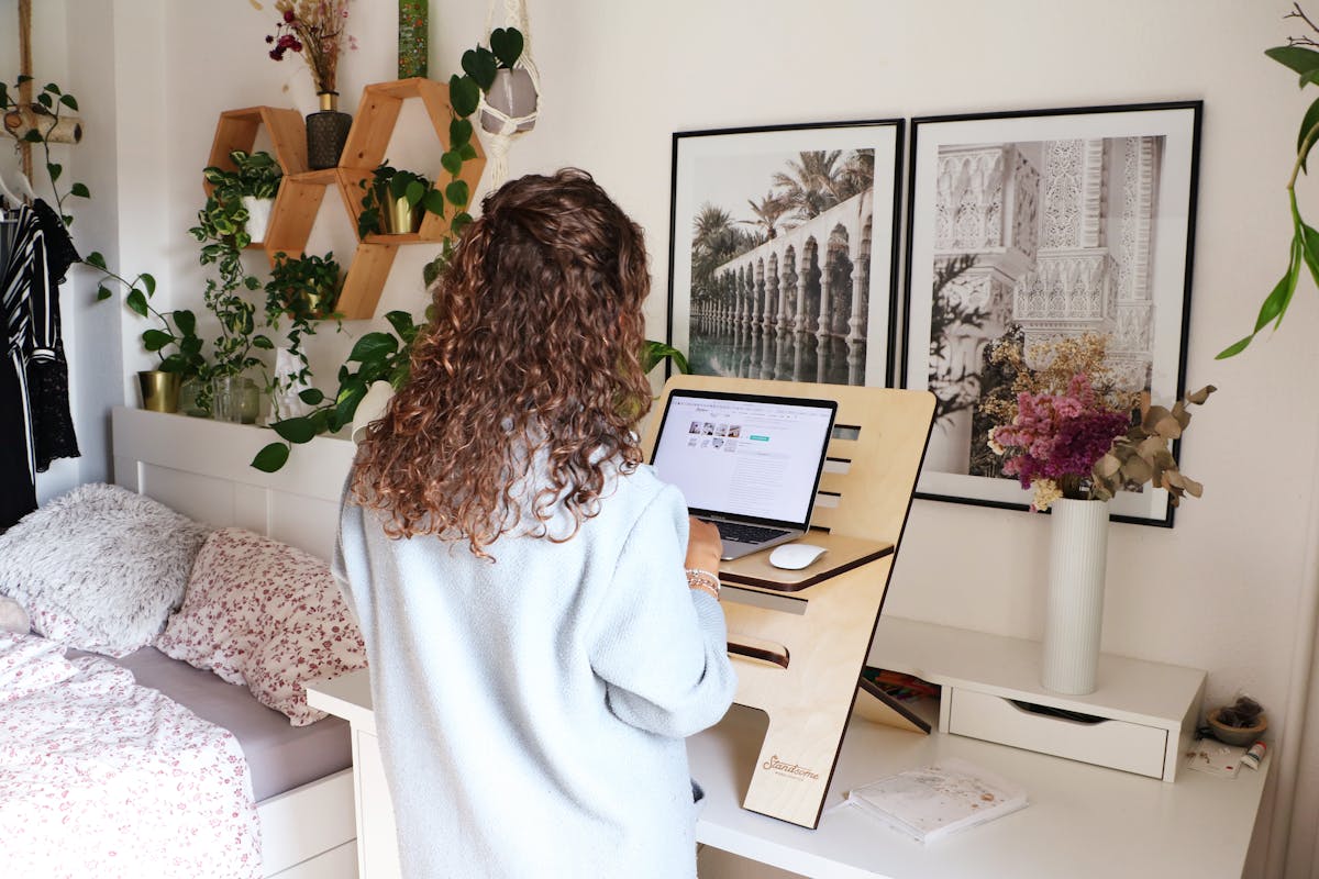 10 Office Exercises You Should Avoid If You Want to Stay Sluggish 3 Woman using a laptop at home office standing desk with decor and laptop.