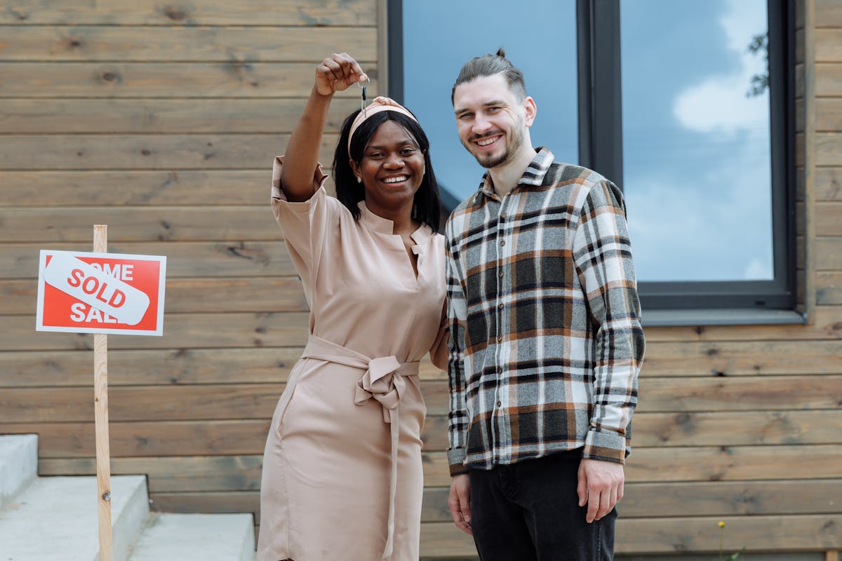 8 Tax Fights That Could Financially Ruin Millions of Americans in 2026 3 Young couple celebrates buying their first house with keys in hand and a sold sign.