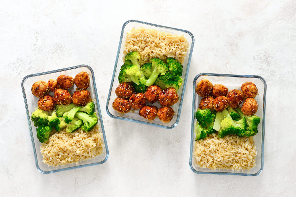 Asian style teriyaki sauce chicken meat balls with broccoli and rice prepared and put in a take away lunch boxes, view from above