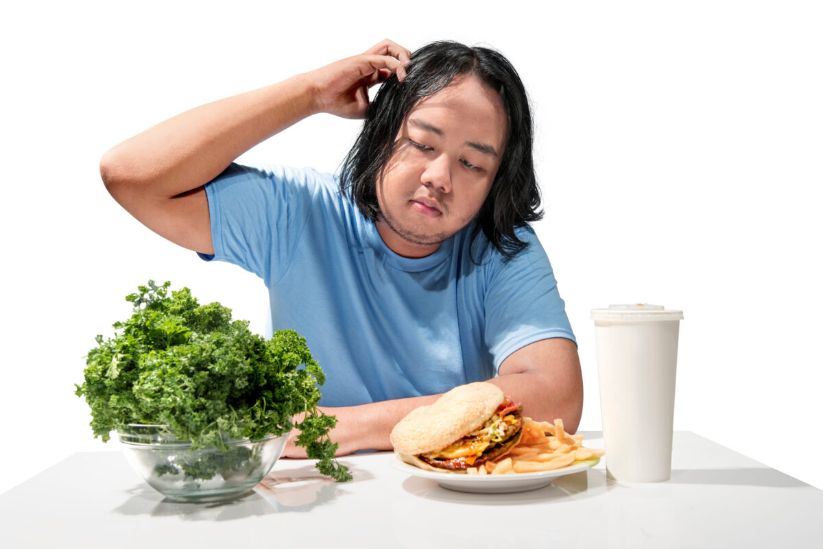 Young asian fat man confused choosing between fast food or healthy food isolated over white background. Fat man diet concept