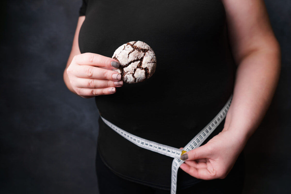 Obese woman with fattening food and measure tape