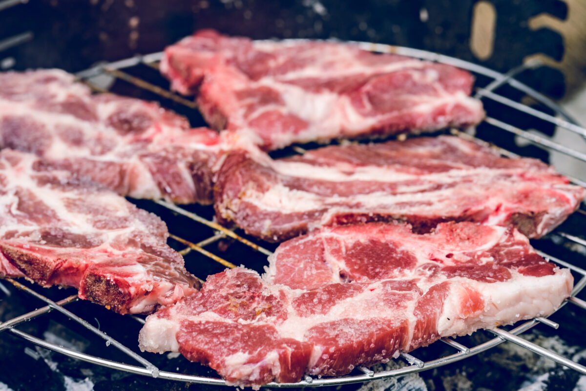 Close up on red pork pig meat cooking on the barbeque outdoor grill food