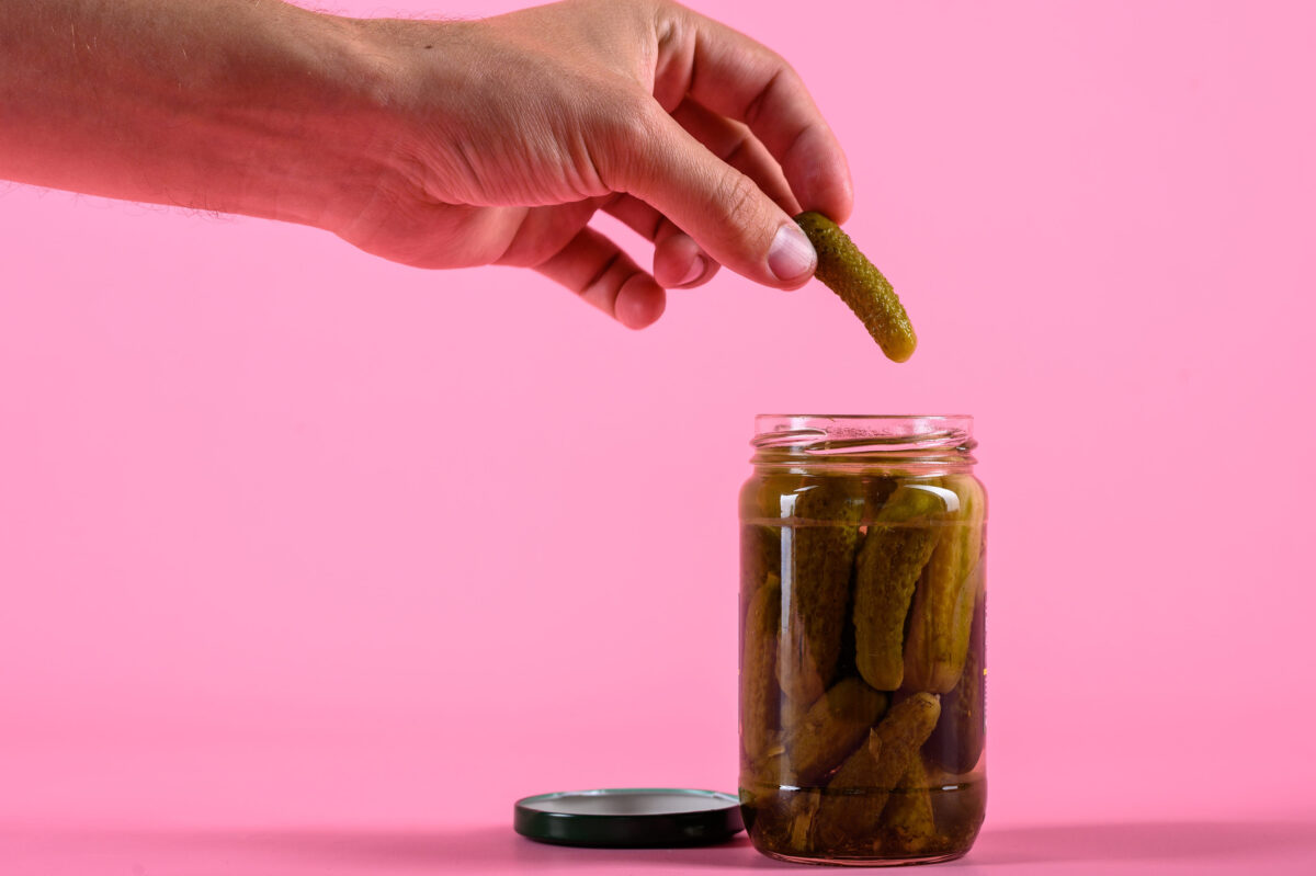 Pickled cucumbers with herbs and spices on pink background. Mock up