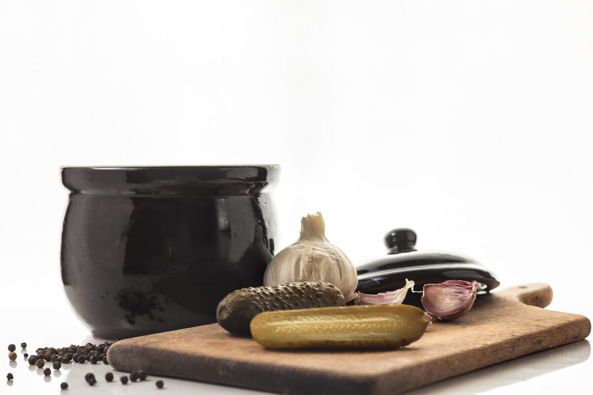 Pickled cucumbers in a stone dish.  Sliced cucumbers on a wooden board.. White background. Polish cuisine. Tastes of Europe. Healthy food.