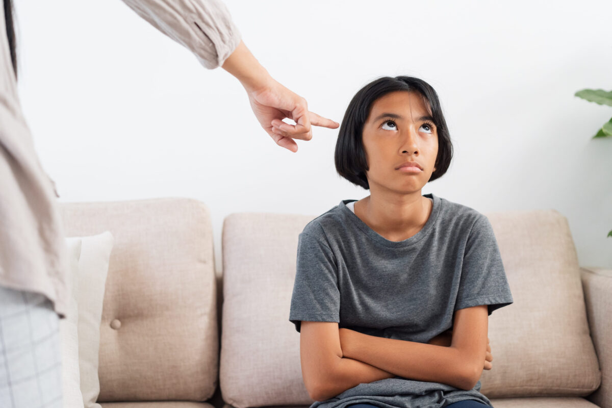 Asian mother is angry and scold her daughter while sitting on the sofa because of bad behavior. The concept of domestic violence.