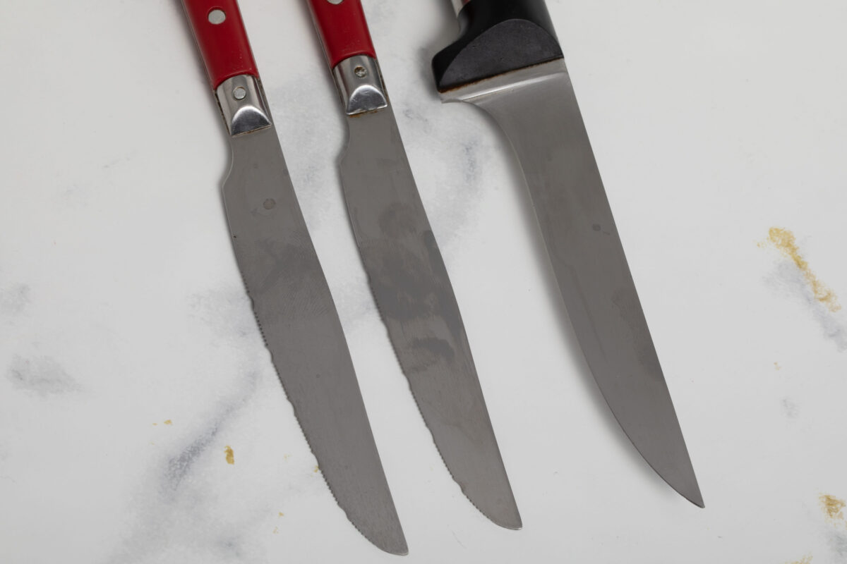A sharp steak knife isolated on white marbler marbackground with red handle.