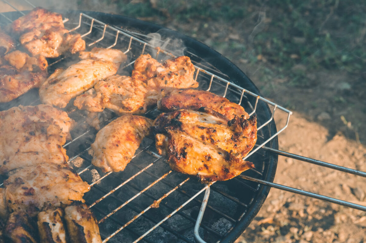 Close up of delicious and juicy chicken meat being cooked on a charcoal barbeque grill. Tasty snack party.