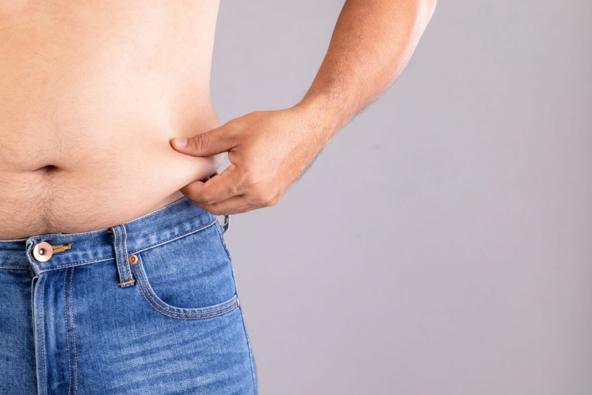 8 Alarming Risks of Excessive Protein and How We Are Pushing Our Bodies Beyond Their Limits 4 Close up fat man pinching his left tummy studio shot on grey background with copy space for text or design. Fat people and healthy concept
