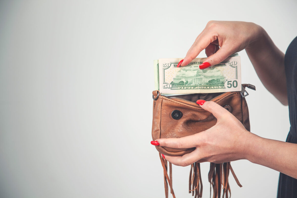 10 Grocery Shopping Methods That’ll Save You Time and Money 3 Young woman pulls out dollar banknotes money from brown wallet bag