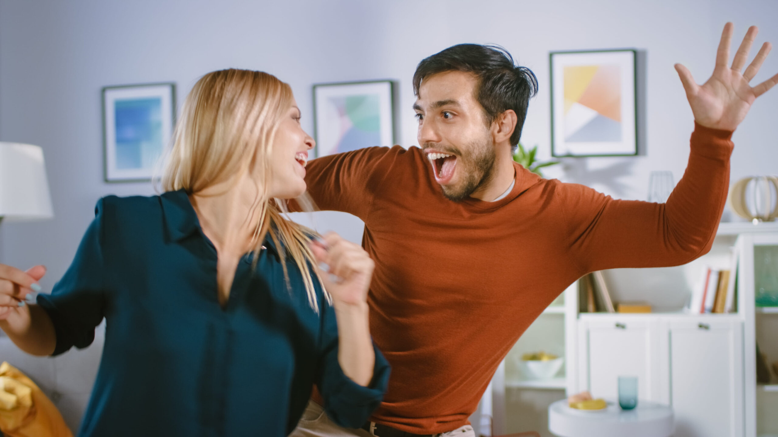 Beautiful Happy Young Couple in Love Dancing in the Middle of the Living Room. Boyfriend and Girlfriend Cheerfully Celebrate by Dancing at Home.
