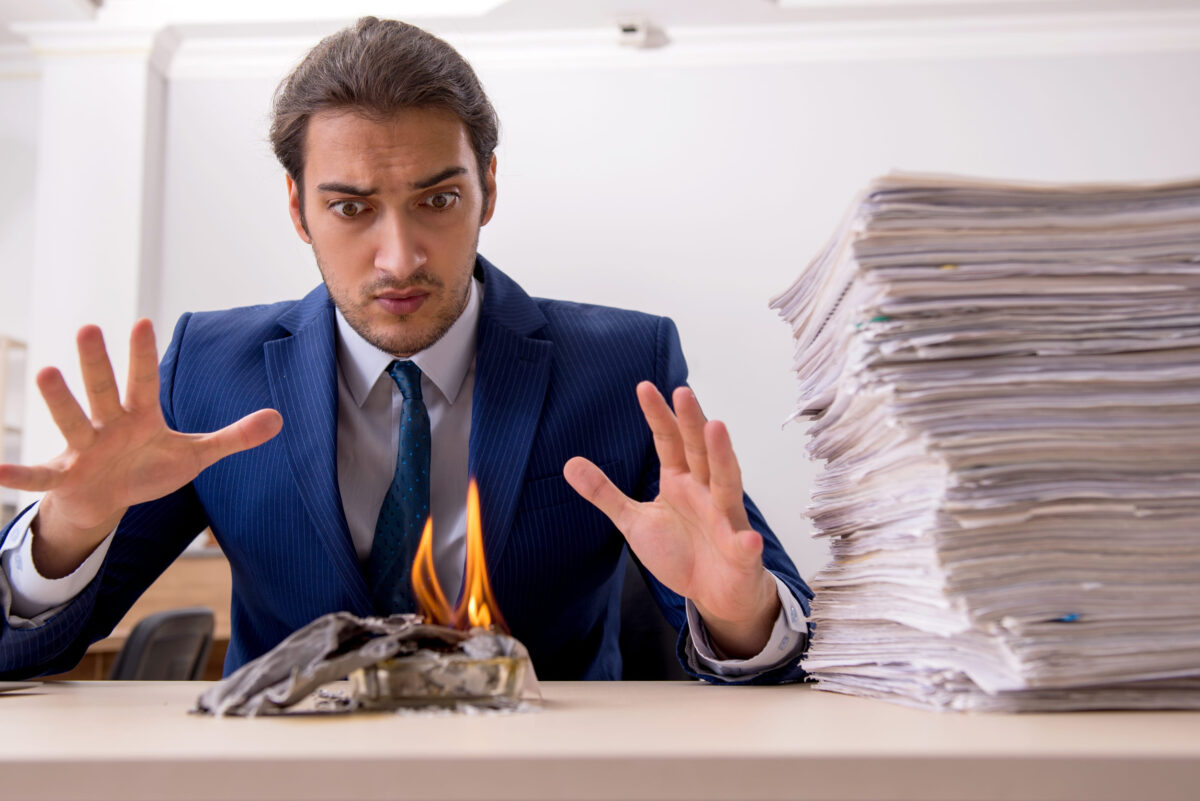 Young male employee burning papers in the office