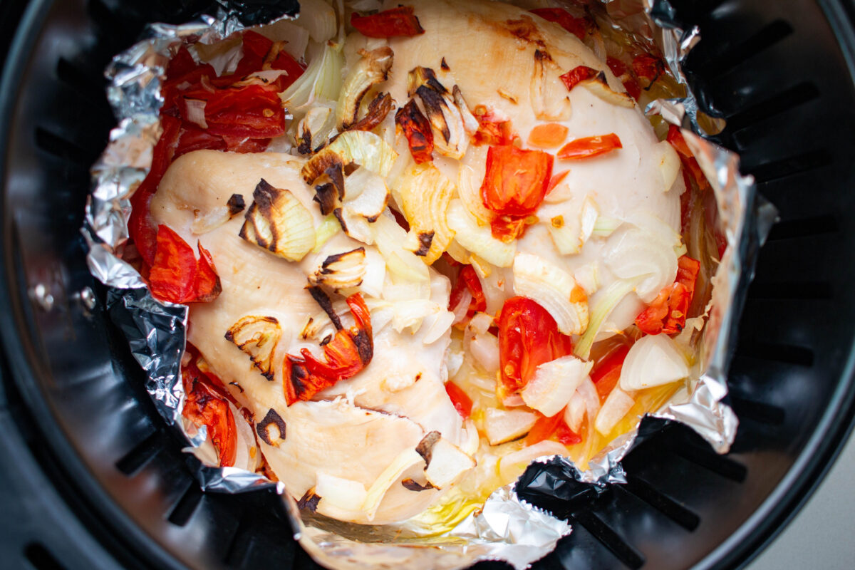 Buttered chicken breast wrapped in foil, onion and tomato mixture