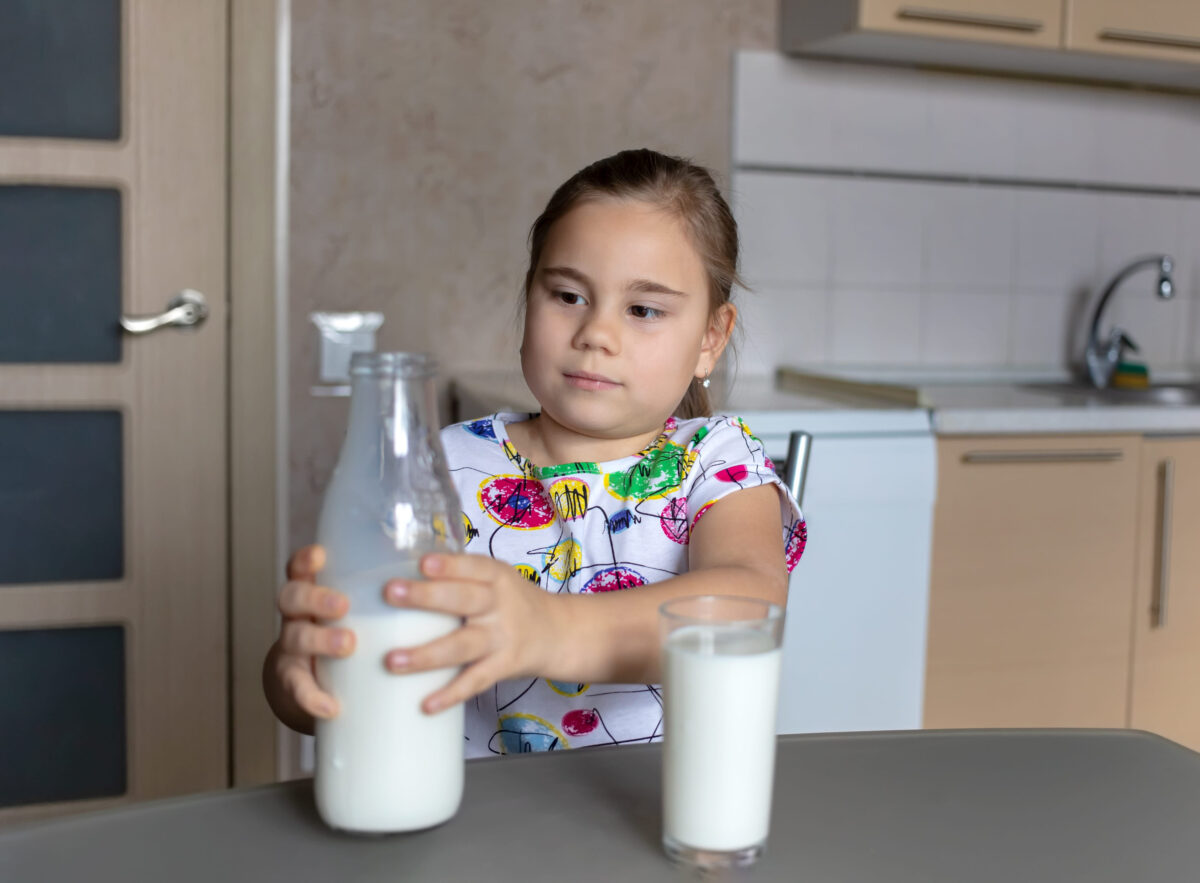 Cute little child girl is drinking milk