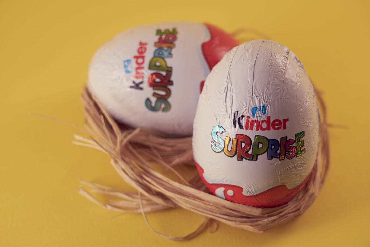 TURKU, FINLAND - FEBRUARY 25, 2021: Kinder Surprise chocolate eggs with a toy in a nest on a yellow background. Easter concept.