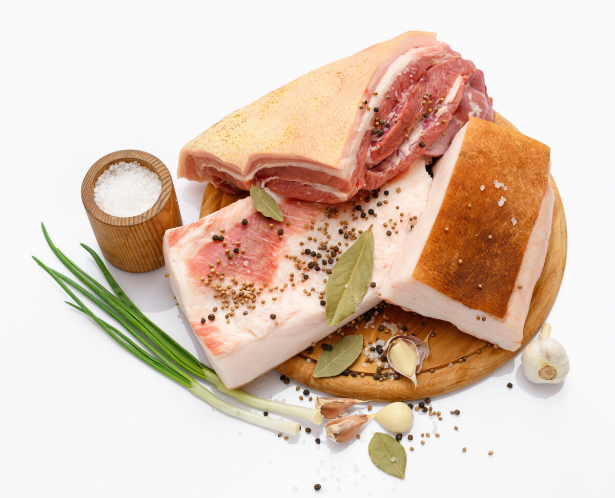 raw pork meat and lard with salt, spices and garlic on a cutting board, white background