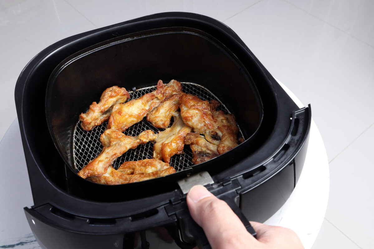 homemade deep fried chicken wings are cooked by using a black air fryer or oil free fryer for being a dinner during the christmas party