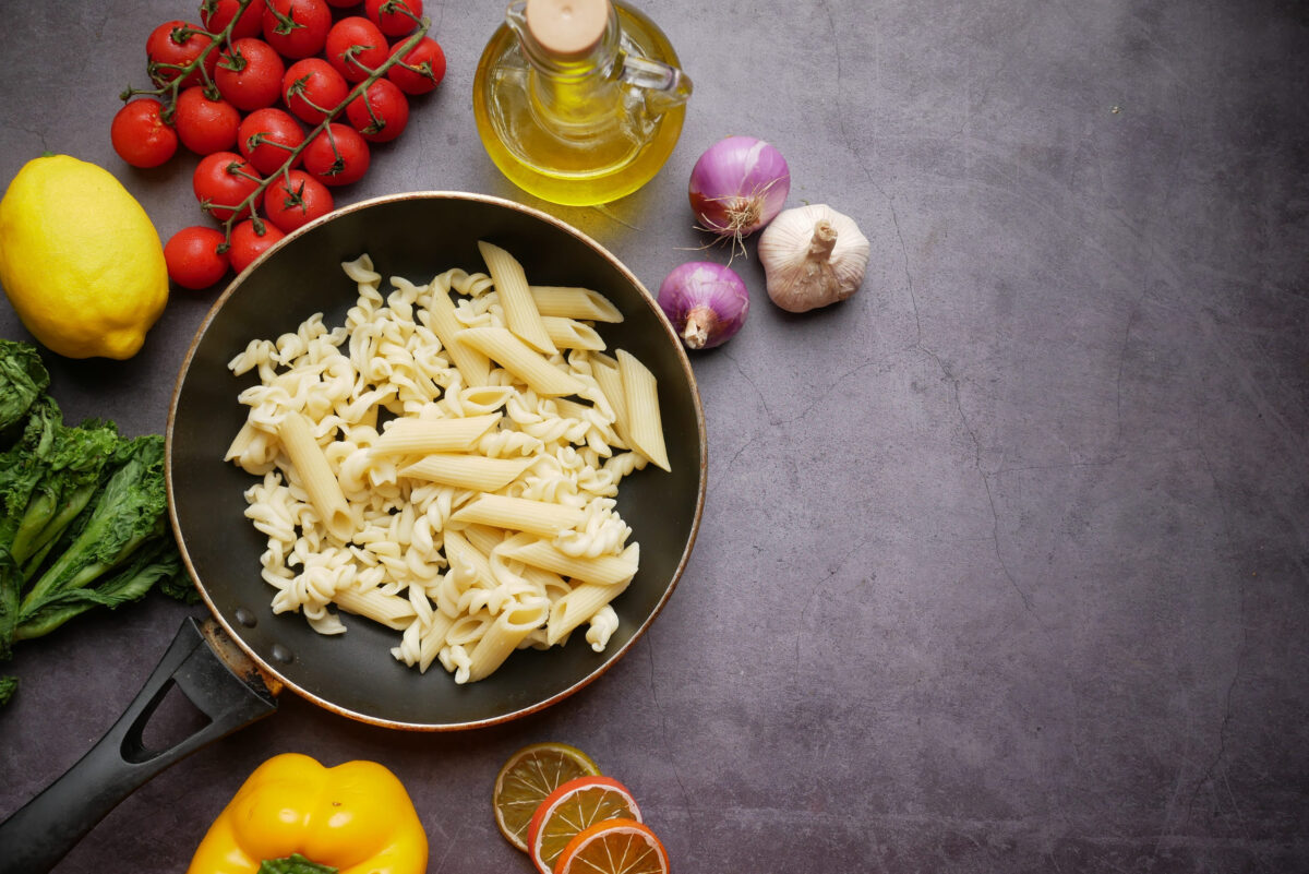 fusilli in a pan on black background.
