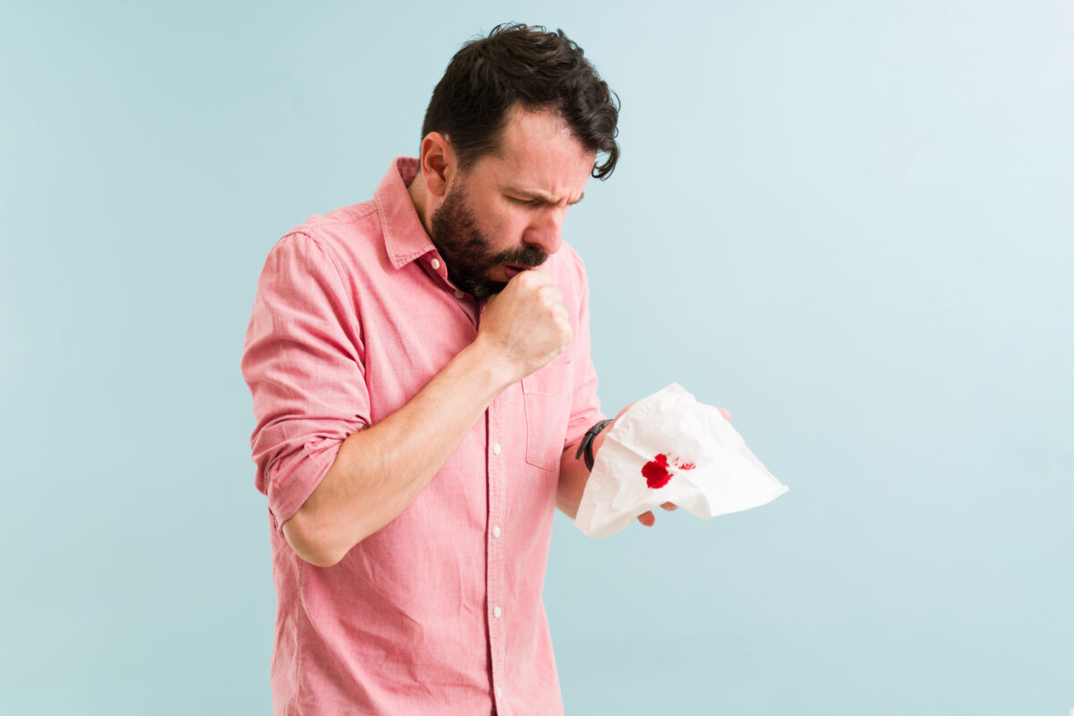Adult man coughing blood because of respiratory problems and in his lungs. Latin man sick with pneumonia illness