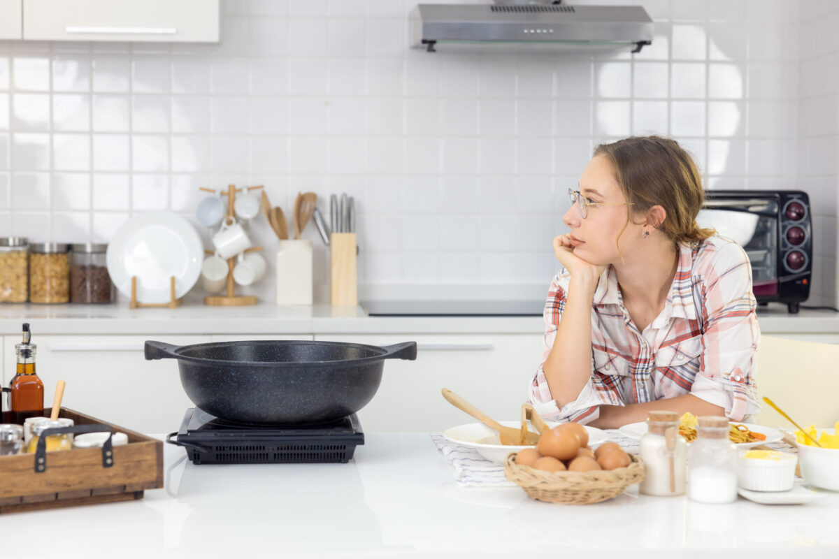 8 Common Cooking Mistakes That Are Quietly Ruining Your Meals 1 In the kitchen at home, a beautiful woman with a tablet prepares a pasta meal, and a lovely young woman eats pasta.
