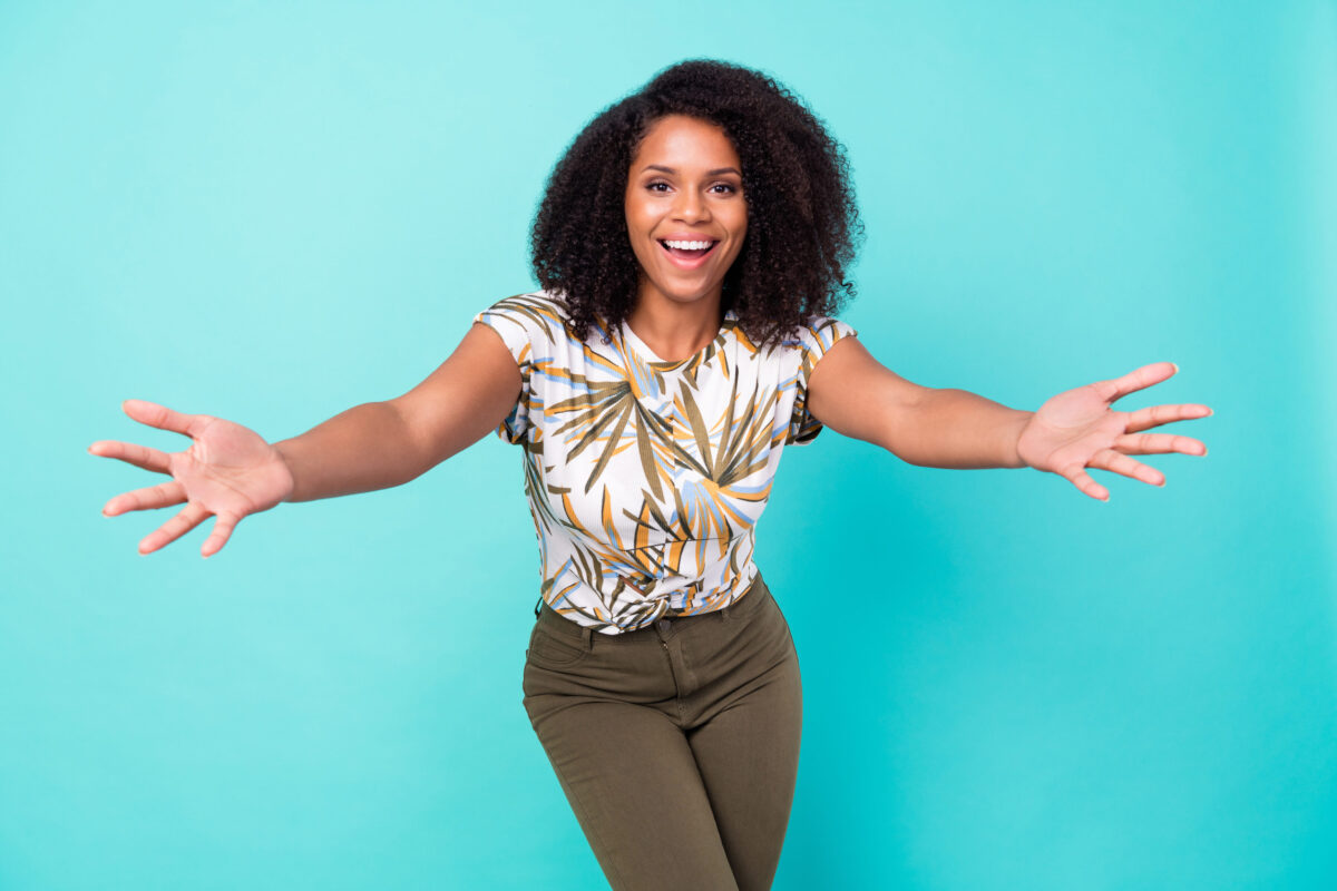 Photo of sweet excited dark skin lady wear print t-shirt smiling ready hug you isolated turquoise color background