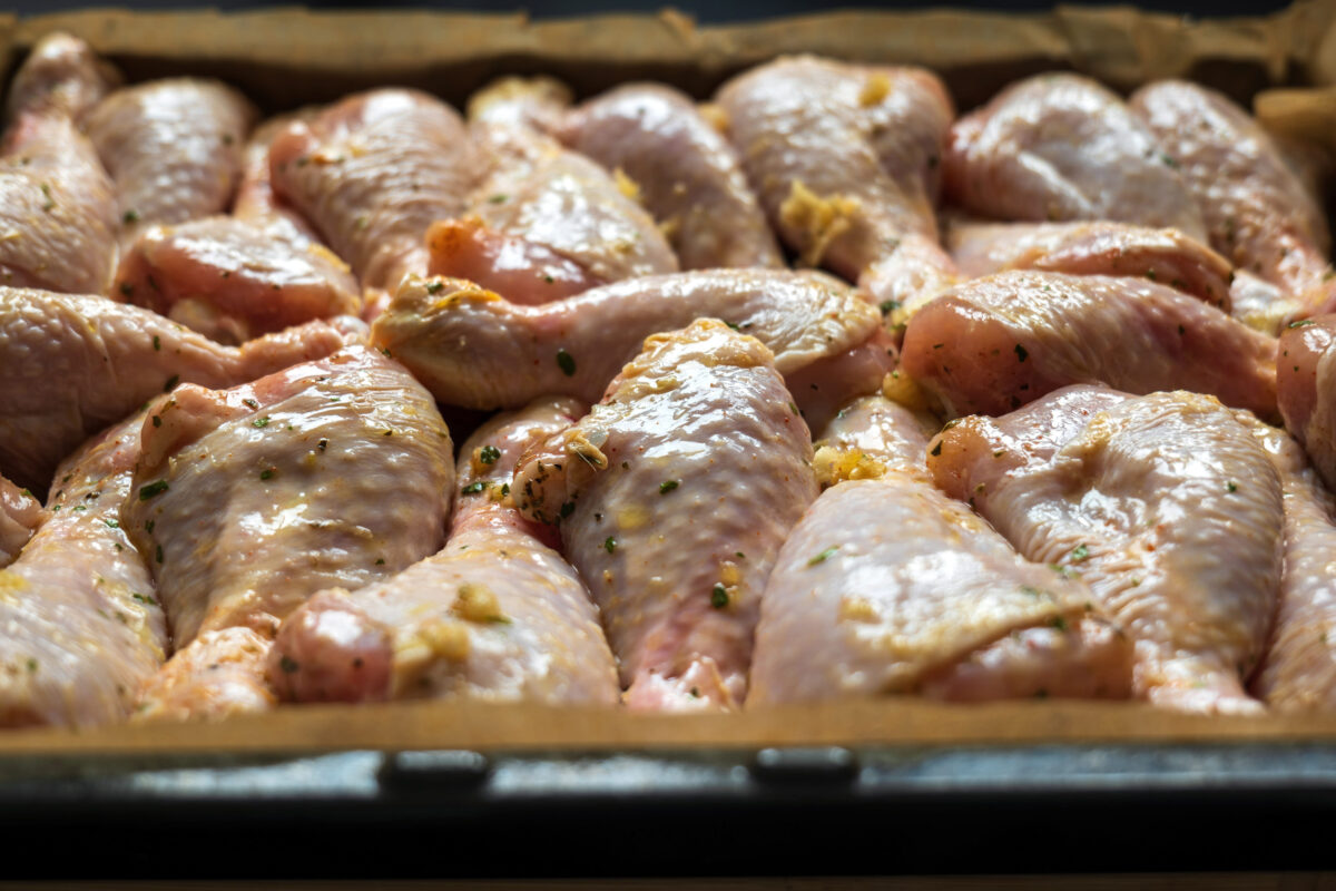 raw chicken drumsticks on baking tray prepared for oven