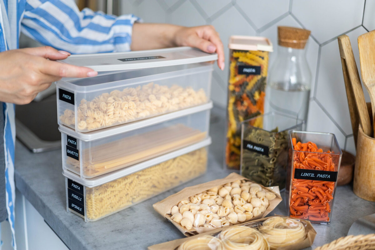 Closeup female hands placing and sorting pasta into pp boxes. Storage organization at kitchen