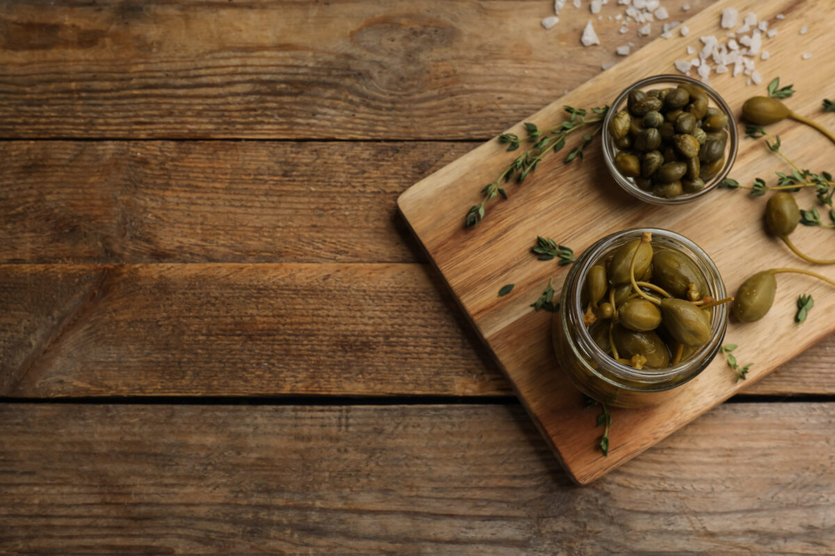 Tasty capers on wooden table, top view. Space for text