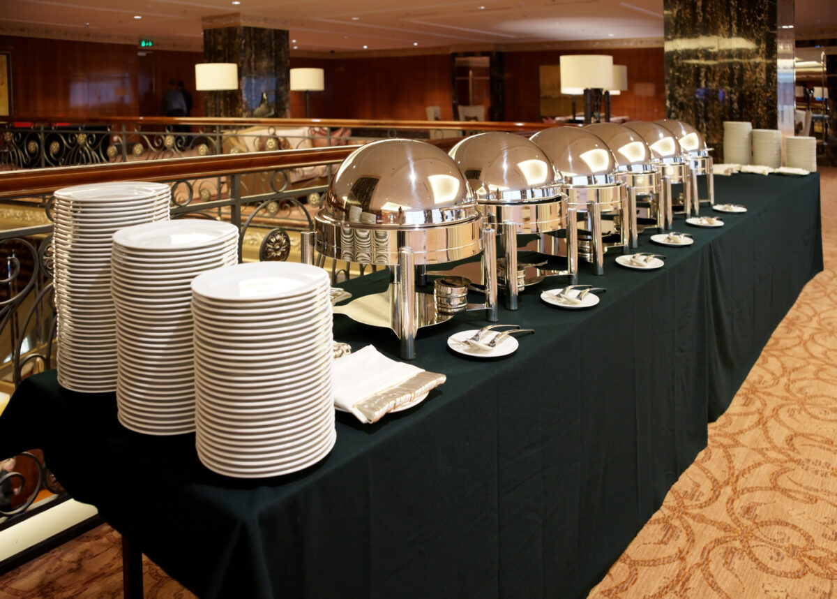 Table with dishware and shiny marmites in hotel lobby